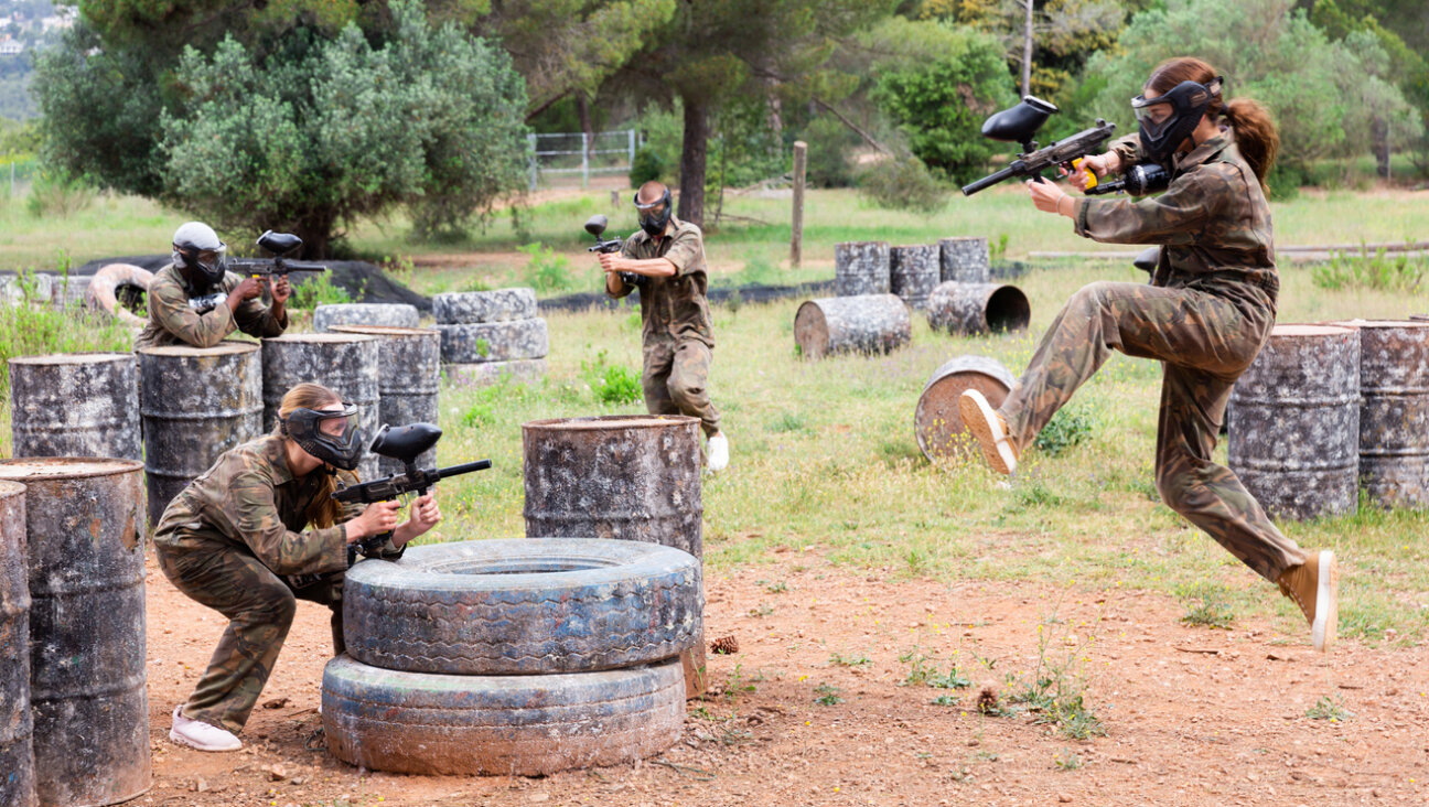 A group plays paintball at an outdoor shooting range. 