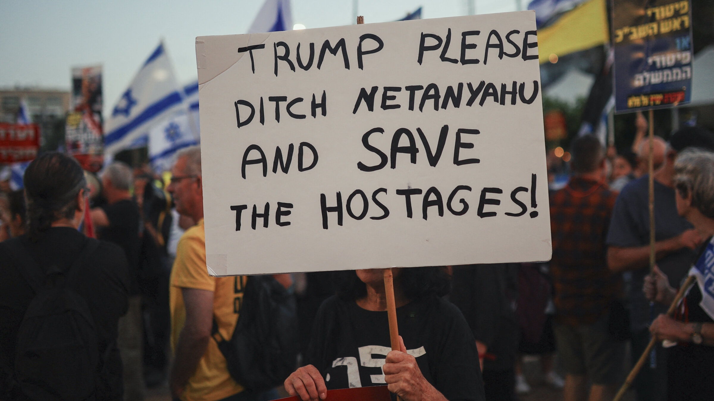 Demonstrators wave Israeli flags and hold signs at a protest in Tel Aviv on May 22.