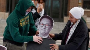 Pro-Palestinian demonstrators adjust a photo of the University of Michigan President Santa Ono as people gather for a mock trial against the University of Michigan’s Board of Regents on the university’s campus in Ann Arbor, Michigan, on April 21, 2025. (Jeff Kowalsky/AFP via Getty Images)