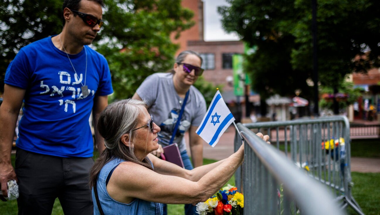 Lisa Turnquist of Louisville, Colorado, lays flowers and a flag at the site of the attack outside the Boulder County Courthouse on June 2, 2025 in Boulder.