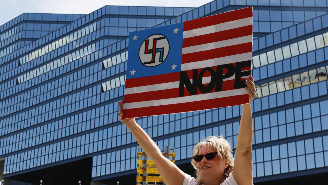 A person holds up a sign in the colors of the American flag with a swastika.