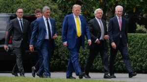 President Donald Trump is accompanied by newly appointed U.S. Ambassador to France Charles Kushner (R) and other guests as they head for a flag-raising ceremony for a newly installed flag pole on the South Lawn of the White House on June 18, 2025 in Washington, D.C. (Chip Somodevilla/Getty Images)