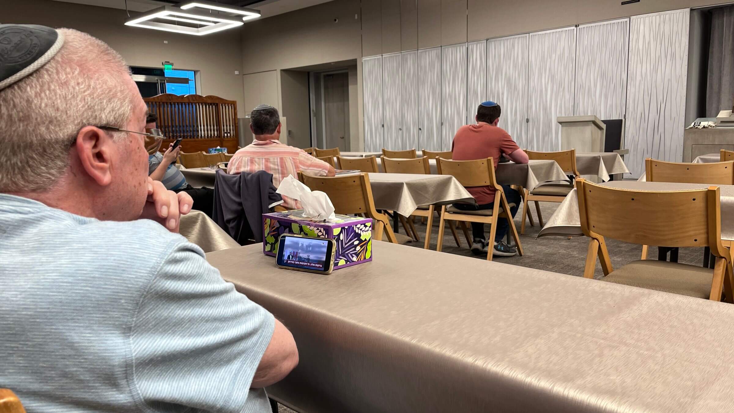 Benny Factor watches Israeli TV on his phone before evening prayers June 12 at Young Israel of Century City, an Orthodox synagogue in Los Angeles.