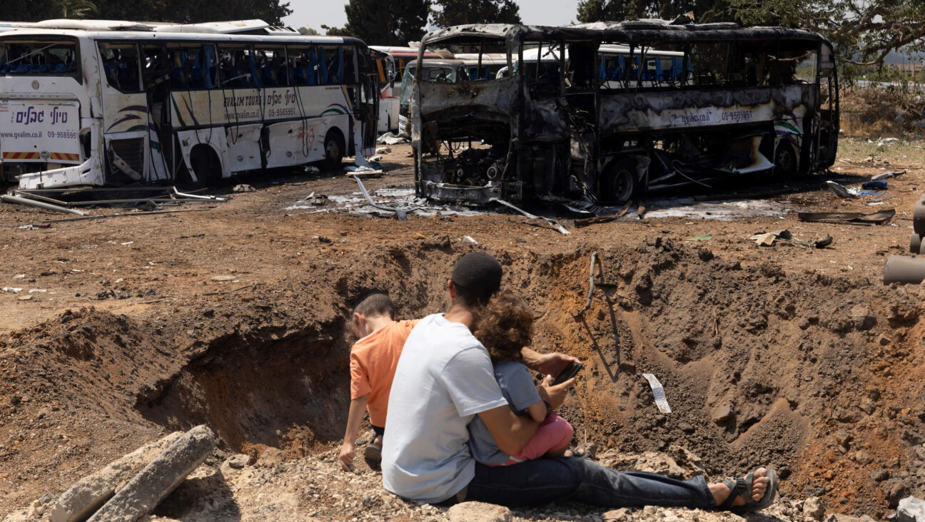 People look at a crater in the ground in the aftermath of a missile strike fired from Iran on June 17 in Herzliya, Israel.