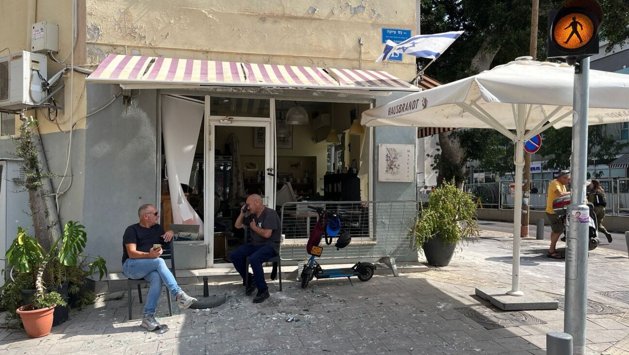 Patrons of a cafe whose windows were shattered by a nearby missile impact sit next to piles of broken glass, Tel Aviv, June 16, 2025. (Niv Elis)