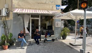 Patrons of a cafe whose windows were shattered by a nearby missile impact sit next to piles of broken glass, Tel Aviv, June 16, 2025. (Niv Elis)