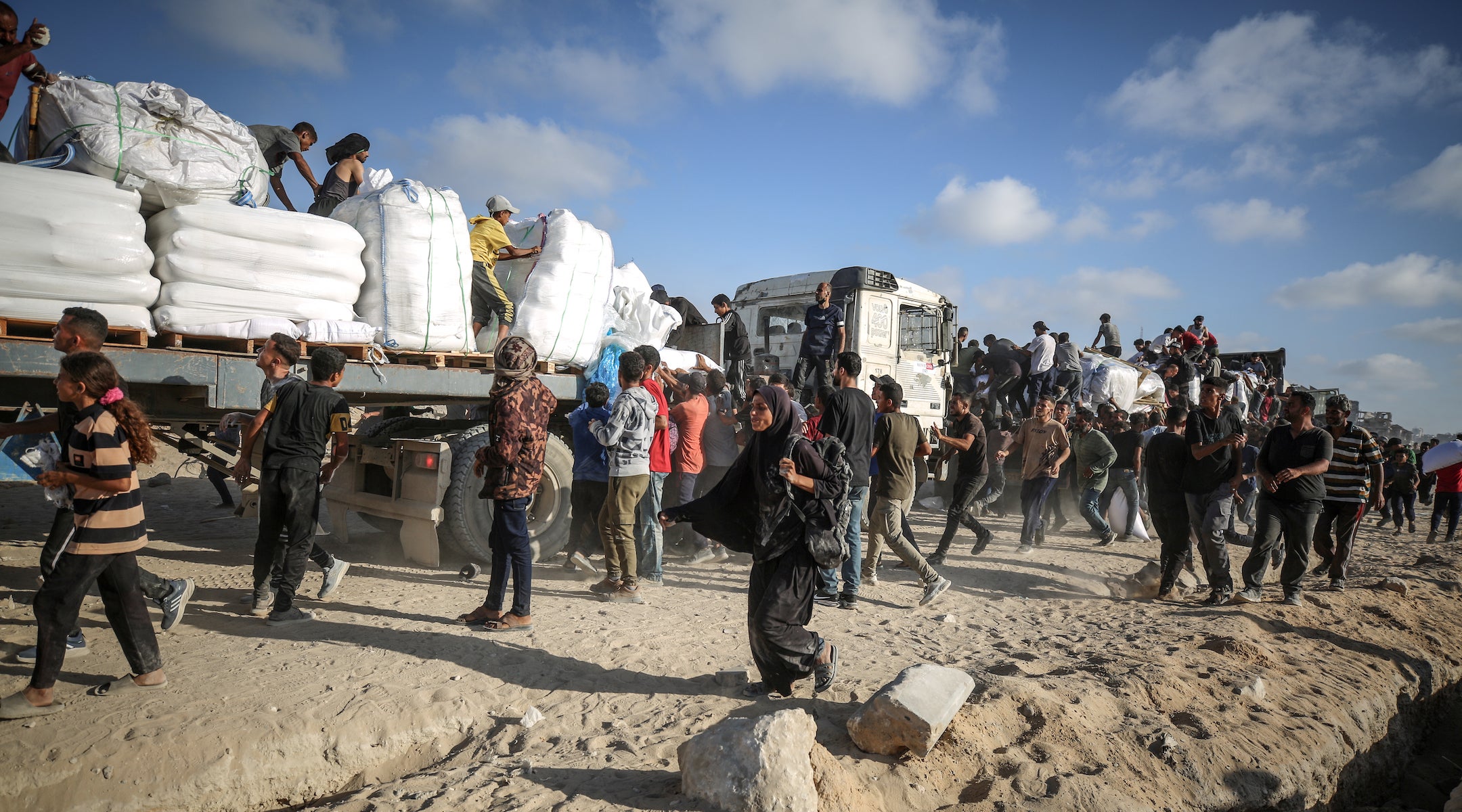 Palestinians receive aid supplies after aid trucks sent by the United Nations under Israeli attacks enter the Zakim border crossing under the protection of Palestinians and reached the warehouses in the north of in Gaza City, Gaza, on June 25, 2025.