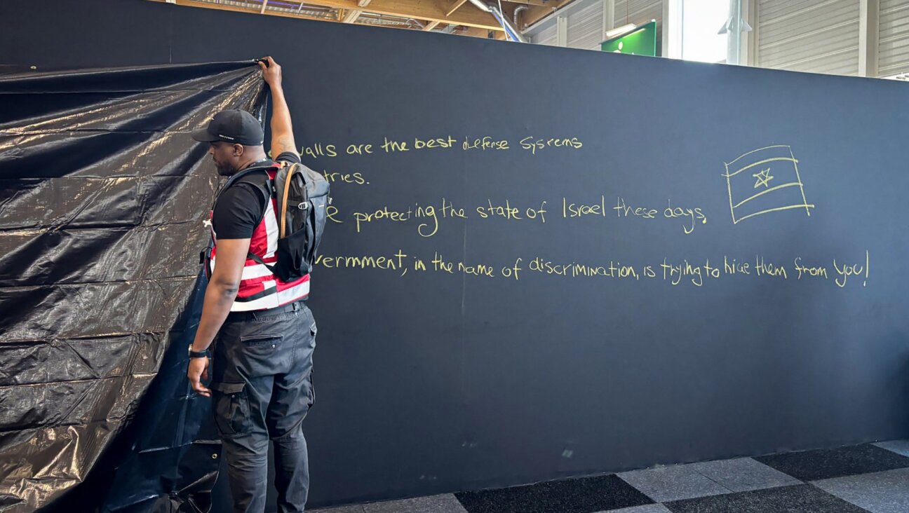 A security personnel works to hide a graffiti reading “Behind these walls are the best defense systems used by many countries. These systems are protecting the state of Israel these days. The French government, in the name of discrimination is trying to hide them from you!”, on a panel of the Israel Aerospace Industries (IAI) Israeli Pavillon during the International Paris Air Show at the Le Bourget Airport on June 16, 2025. (Mathieu RABECHAULT/AFP)