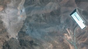 Maxar Satellite Imagery shows the ridge above the Fordow complex in Iran post-strike. Multiple impact craters and a wide grey-blue ash layer are visible across the ridge, suggesting direct hits to the overburden covering the underground facility. (Satellite image (c) 2025 Maxar Technologies)