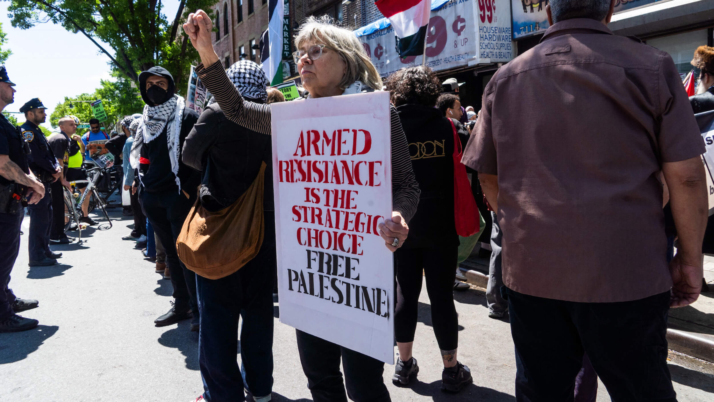 An older woman raises a fist in solidarity while holding a sign that reads "Armed Resistance Is The Strategic Choice Free Palestine" during a Nakba Day protest in Bay Ridge, Brooklyn, on May 10.