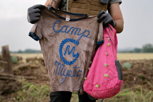 A search and rescue volunteer holds a T-shirt and backpack with the words Camp Mystic on them in Comfort, Texas on July 6. The volunteer found the belongings along the Guadalupe River near Ingram, Texas.  