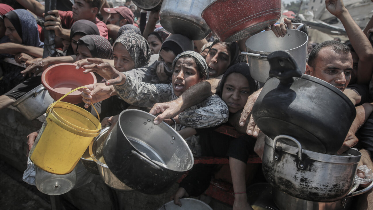 Palestinians hold out pans to receive food from a charity distribution point in Gaza City.