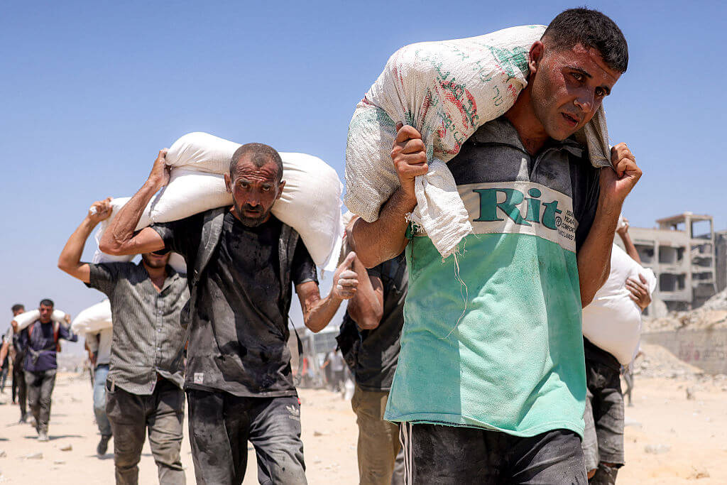 People walk with sacks of flour delivered after trucks carrying humanitarian aid entered northern Gaza on July 27.