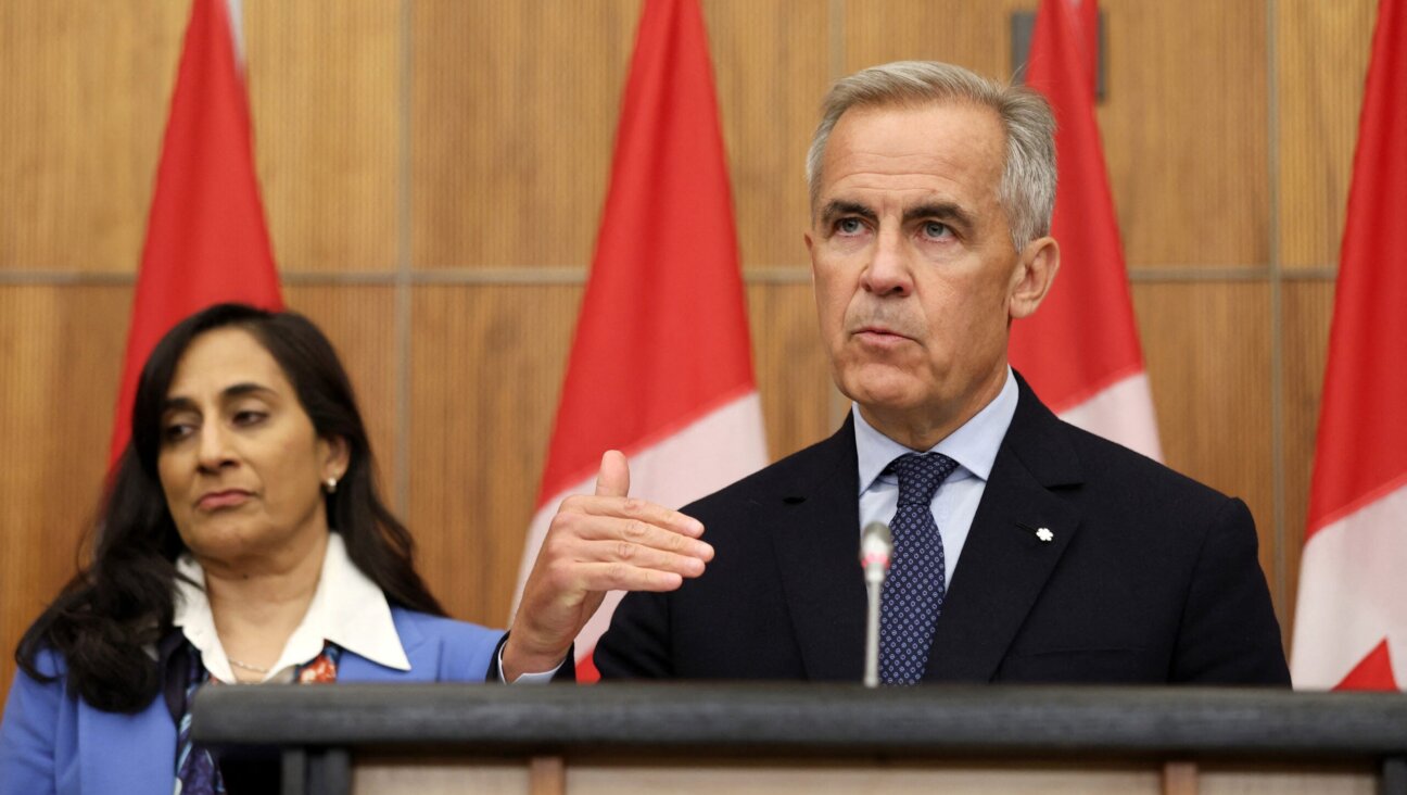 Canadian Prime Minister Mark Carney, flanked by Canadian Foreign Affairs Minister Anita Anand, speaks during a press conference at the National Press Theatre in Ottawa, Ontario, Canada on July 30, 2025.