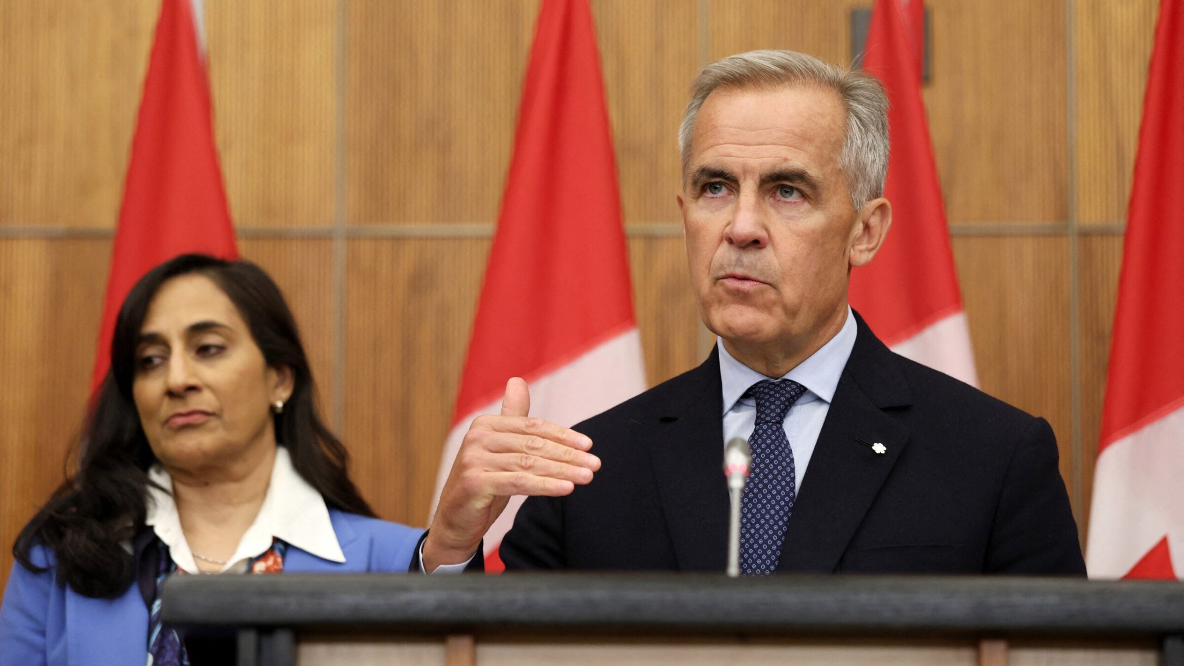 Canadian Prime Minister Mark Carney, flanked by Canadian Foreign Affairs Minister Anita Anand, speaks during a press conference at the National Press Theatre in Ottawa, Ontario, Canada on July 30, 2025.