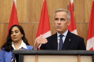 Canadian Prime Minister Mark Carney, flanked by Canadian Foreign Affairs Minister Anita Anand, speaks during a press conference at the National Press Theatre in Ottawa, Ontario, Canada on July 30, 2025.