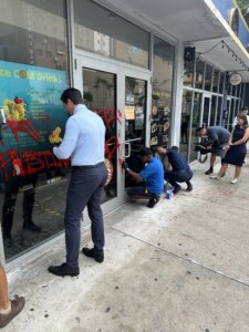 Community members help clean up graffiti at Holy Bagels & Pizzeria in Miami after vandalism in June 2024.