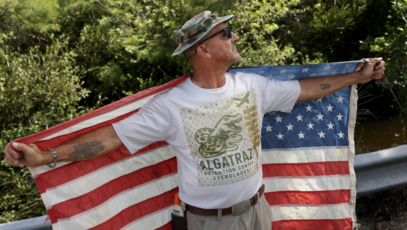 Marc Ribas holds a flag and wears independently produced merchandise advertising "Alligator Alcatraz," the new state-managed immigrant detention facility in Ochopee, Florida, on July 12.  