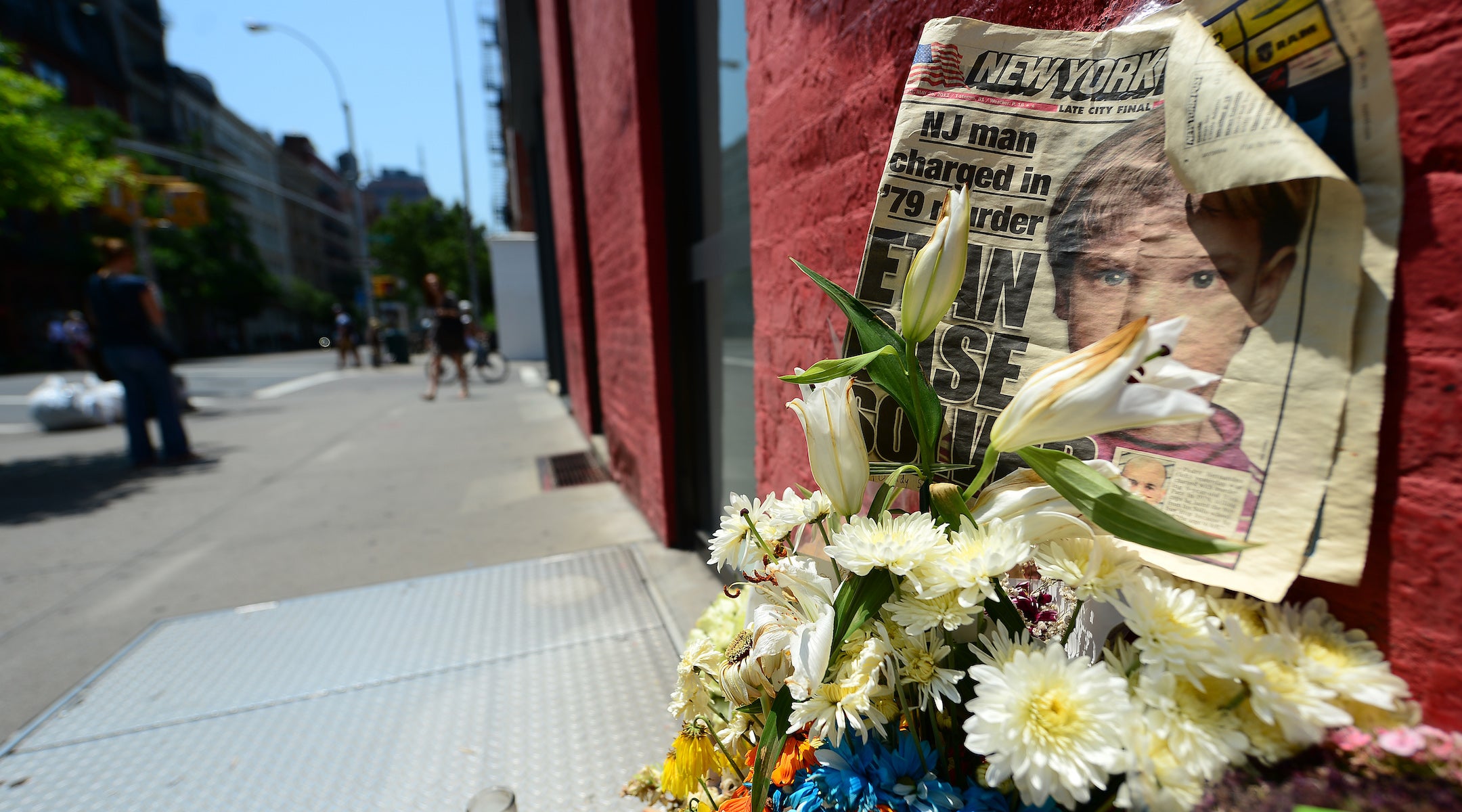 People walk past a street shrine to six-year-old Etan Patz, who went missing in 1979, set in front of the building where suspect Pedro Hernandez confessed to having strangled the boy in New York on May 29, 2012. (EMMANUEL DUNAND/AFP/GettyImages)