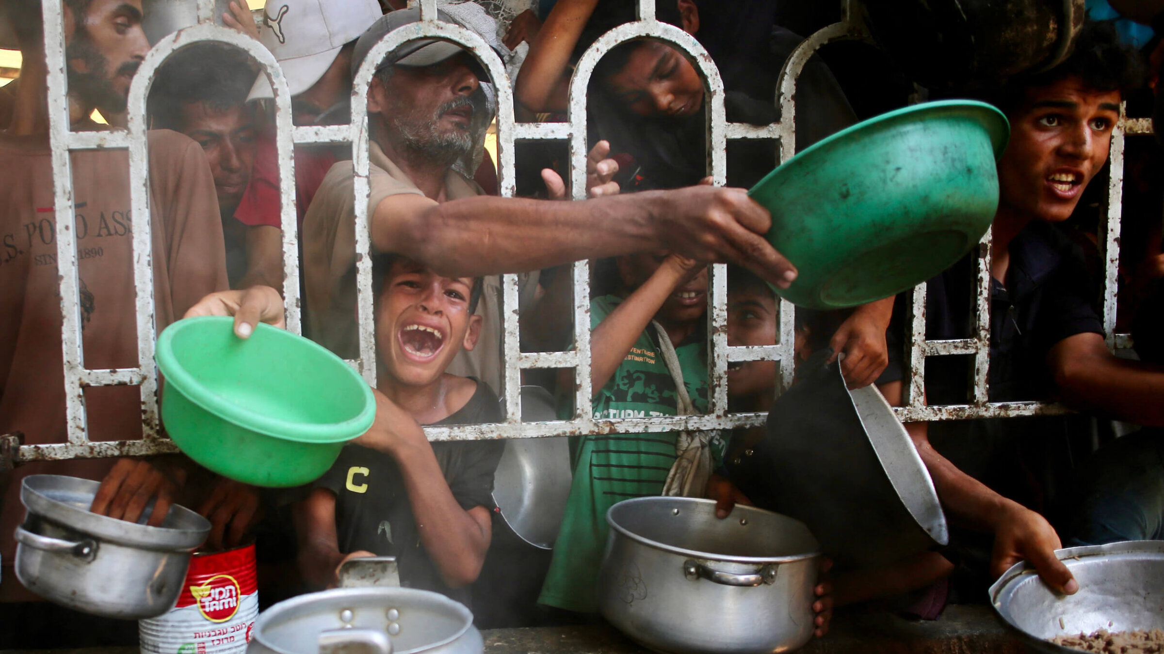 Palestinians struggle to receive a hot meal at a charity kitchen in Khan Younis in Gaza on July 22.