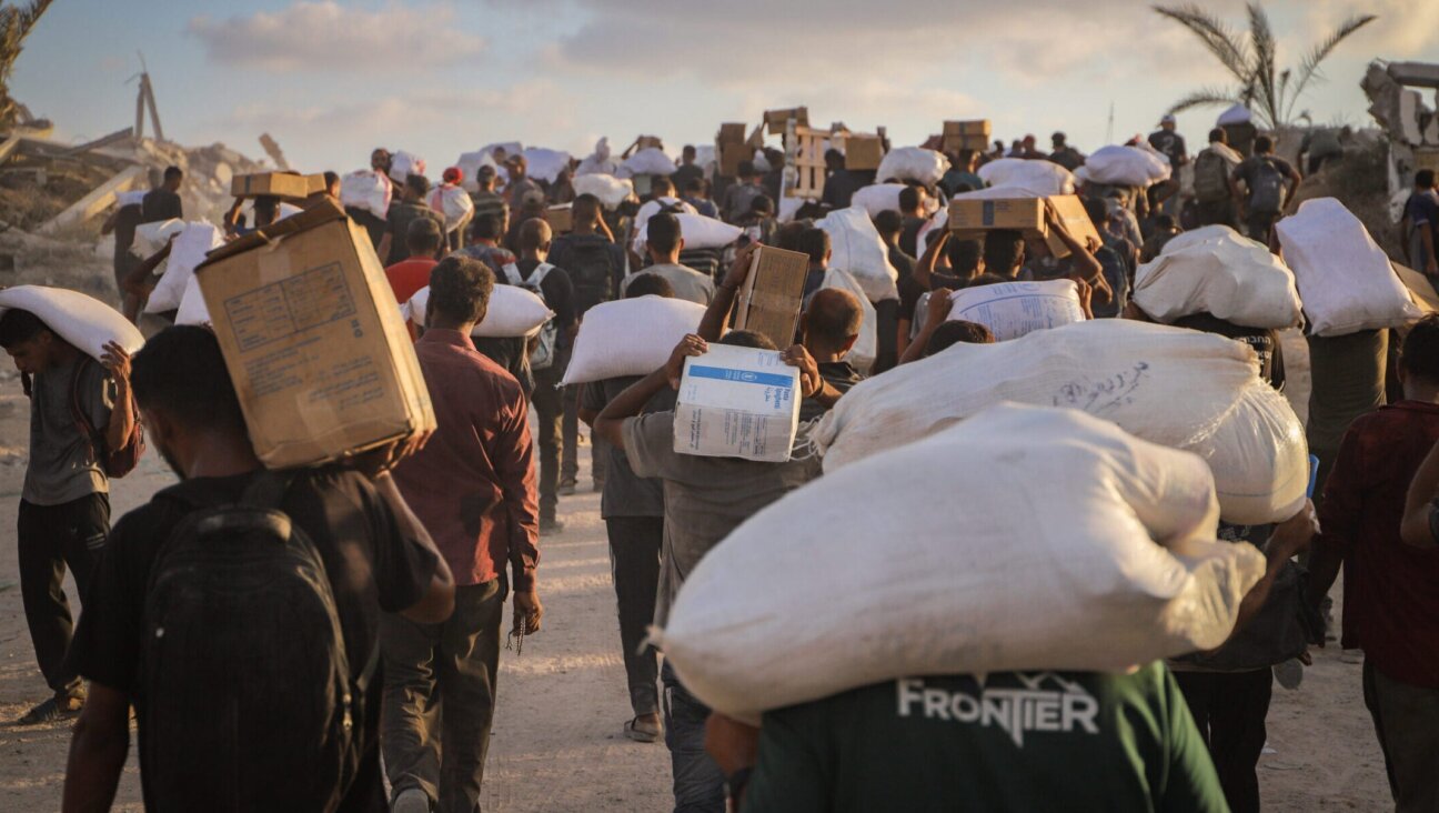 Displaced Palestinians carry food parcels and supplies from aid trucks near the Zikim border crossing between Israel and Beit Lahia, in the northern Gaza Strip, Aug. 18, 2025.
