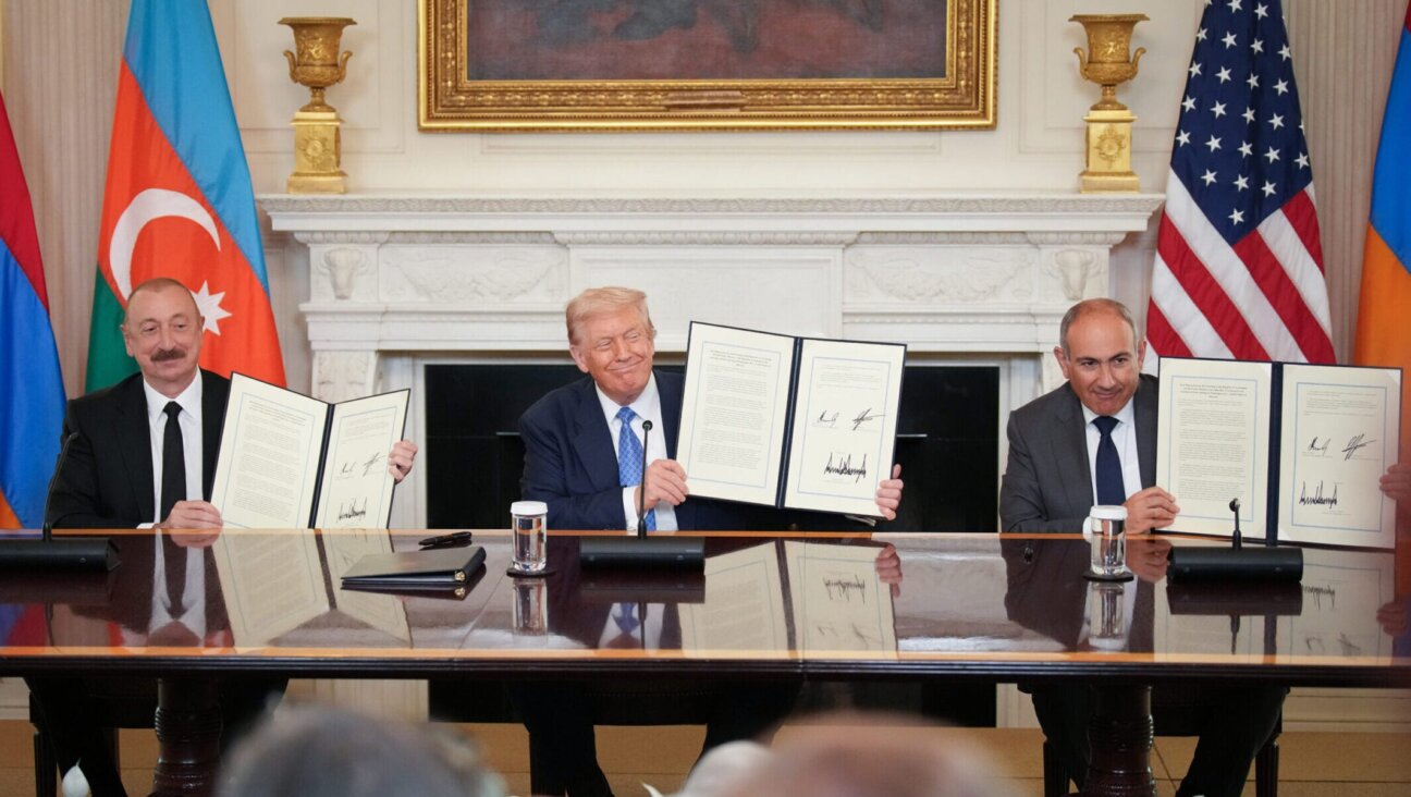 U.S. President Donald Trump, flanked by Azerbaijani President Ilham Aliyev (L) and Armenian Prime Minister Nikol Pashinyan (R) hold up an agreement signed during a ceremony in the State Dining Room of the White House on Aug. 8, 2025.