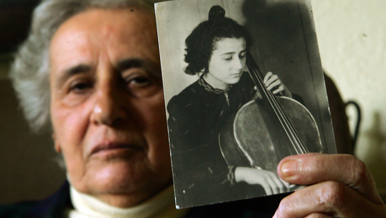 Holocaust survivor Anita Lasuer holds up a portrait of herself playing the cello. She survived Aucshwitz in part, because she played in the orchestra.   