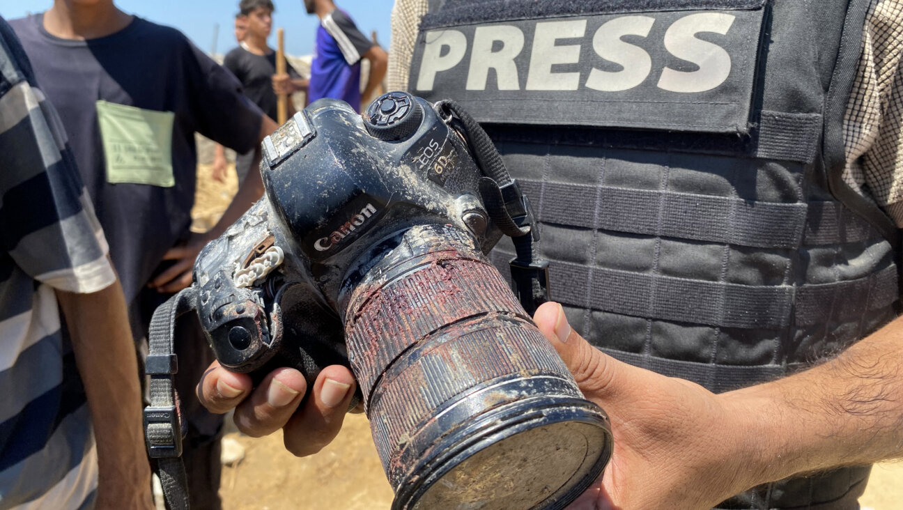 A journalist holds the blood-covered camera belonging to Palestinian photojournalist Mariam Dagga, a journalist who freelanced for AP who was killed in an Israeli strike on Nasser Hospital in Gaza, Aug. 25. 