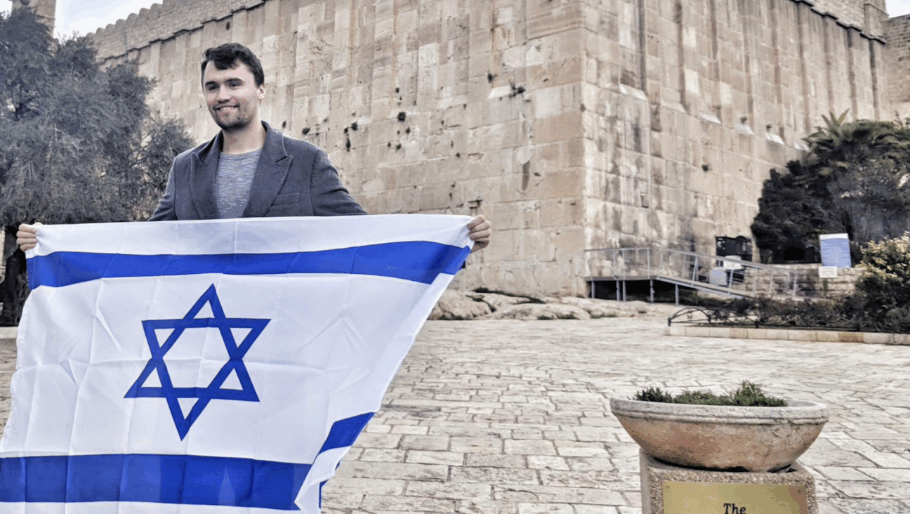 Charlie Kirk holds an Israeli flag outside the Cave of the Patriarchs in the West Bank. 