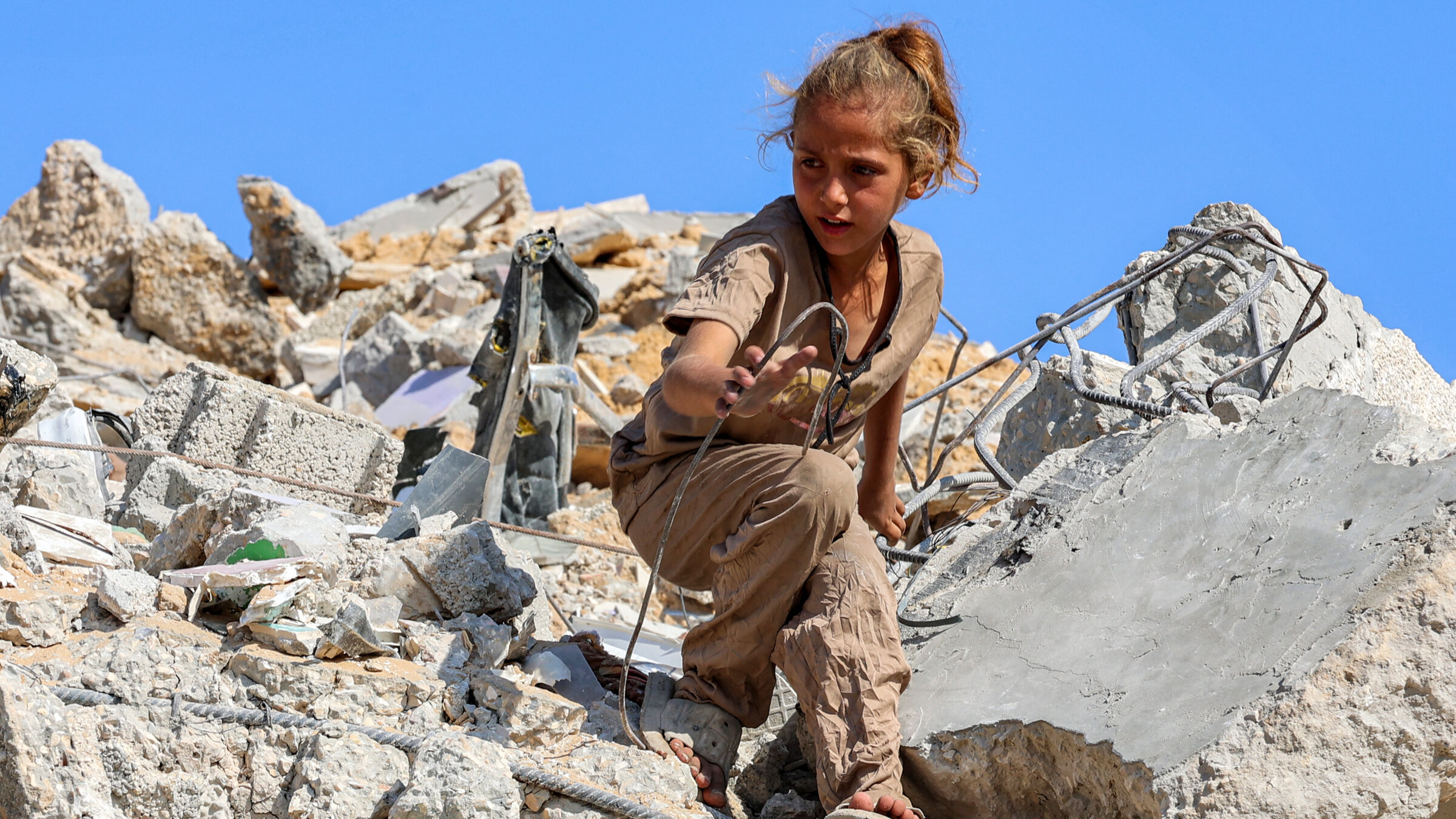 A Palestinian girl searches for salvage in the rubble of a bombed high rise building, Gaza City, Sept. 6.