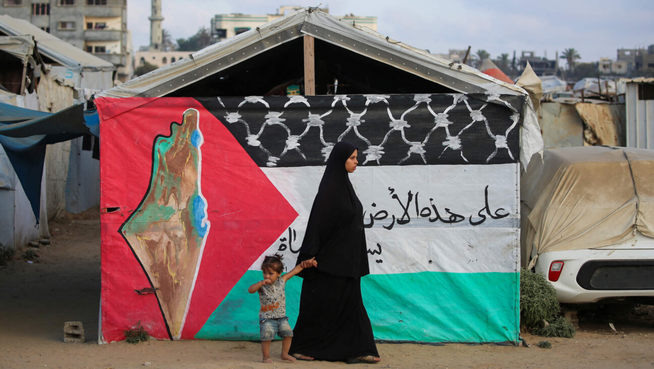 A Palestinian woman walks with a child past a Palestinian flag at the Bureij camp for refugees in the central Gaza Strip on Sept. 22.