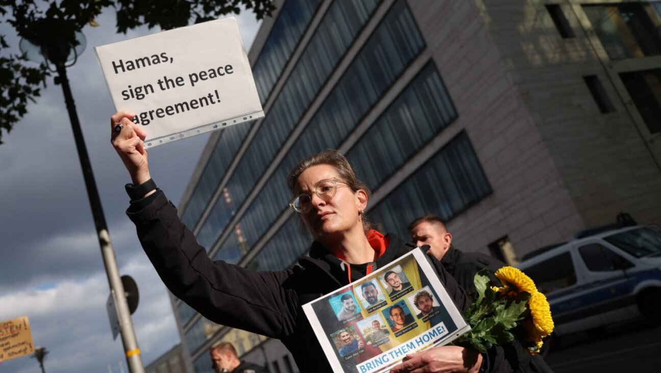 A woman holds a placard that reads: “Hamas, sign the peace agreement!” while holding photographs of German citizens who are among the hostages still being held by Hamas in Gaza during a demonstration outside the Foreign Ministry on Oct. 2, 2025, in Berlin. 