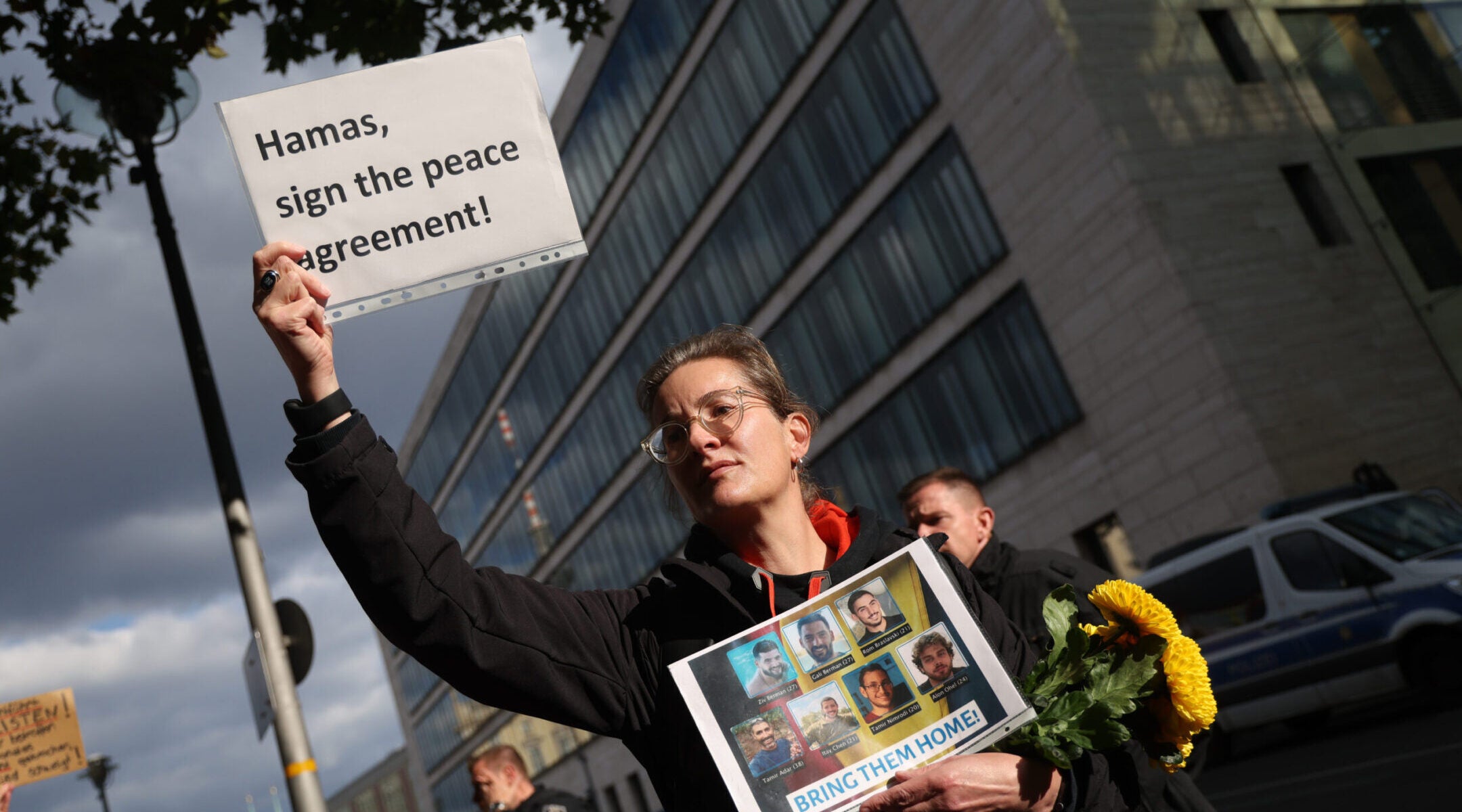 A woman holds a placard that reads: “Hamas, sign the peace agreement!” while holding photographs of German citizens who are among the hostages still being held by Hamas in Gaza during a demonstration outside the Foreign Ministry on Oct. 2, 2025, in Berlin. 