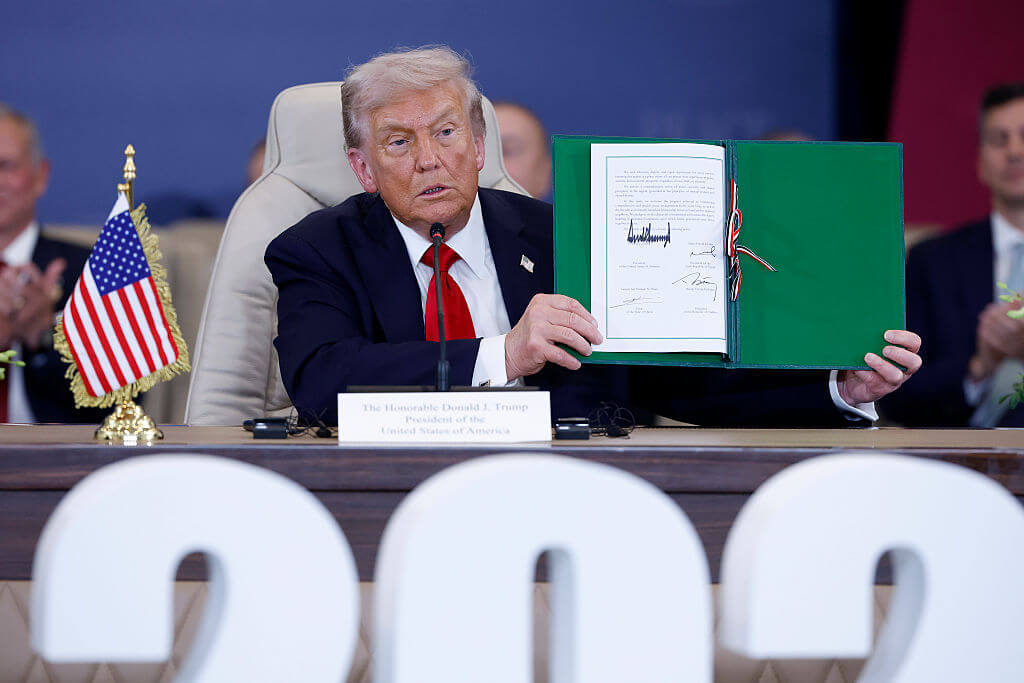 President Donald Trump holds up a signed Gaza ceasefire agreement at a summit in Egypt. 