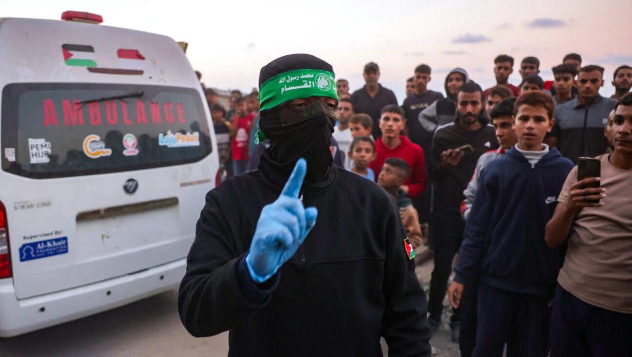 A Hamas member gestures as people gather around an ambulance carrying a body retrieved from a tunnel in an area north of Khan Yunis in Gaza on Oct. 28.