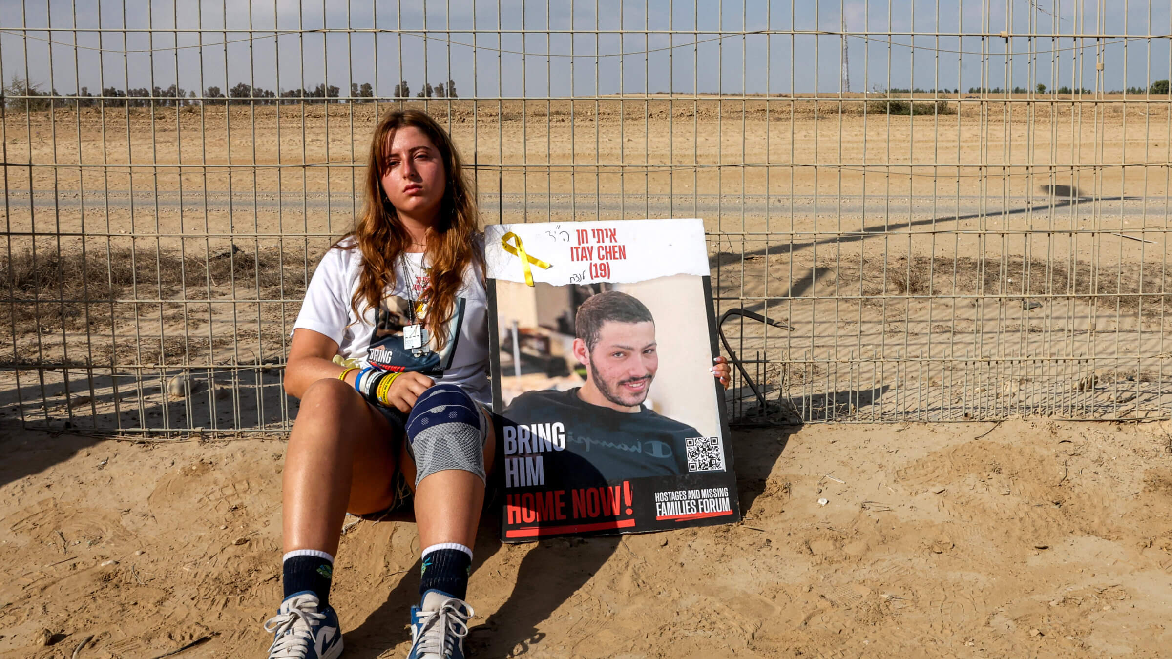 A woman sits with a sign identifying Itay Chen, an Israeli soldier missing since the October 7 attacks by Palestinian militants and confirmed dead by the Israeli army, during a demonstration by the families of the hostages calling for their release, near Kibbutz Nirim in southern Israel by the border with Gaza on August 29, 2024 amid the ongoing conflict in the Palestinian territory between Israel and Hamas. (Photo by JACK GUEZ / AFP) (Photo by JACK GUEZ/AFP via Getty Images)
