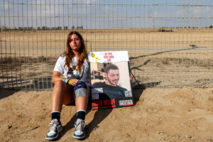 A woman sits with a sign identifying Itay Chen, an Israeli soldier missing since the October 7 attacks by Palestinian militants and confirmed dead by the Israeli army, during a demonstration by the families of the hostages calling for their release, near Kibbutz Nirim in southern Israel by the border with Gaza on August 29, 2024 amid the ongoing conflict in the Palestinian territory between Israel and Hamas. (Photo by JACK GUEZ / AFP) (Photo by JACK GUEZ/AFP via Getty Images)