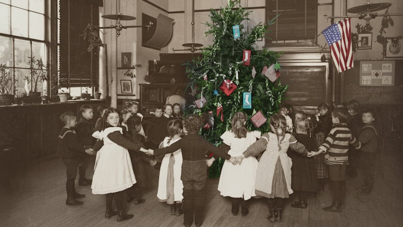 Children hold hands around a Christmas tree in a New York City school, circa. 1900. 