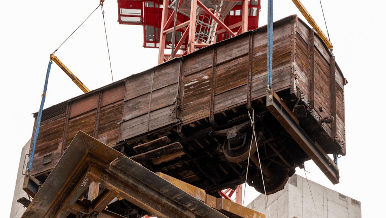 A 173-foot tower crain hoists a 20th century 12-ton railcar into the upcoming Holocaust Museum Boston. 