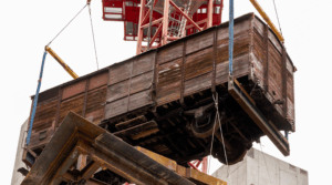 A 173-foot tower crain hoists a 20th century 12-ton railcar into the upcoming Holocaust Museum Boston. 