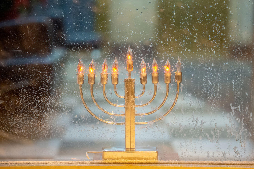 A Hanukkah menorah is displayed in a window on the seventh night of the holiday.