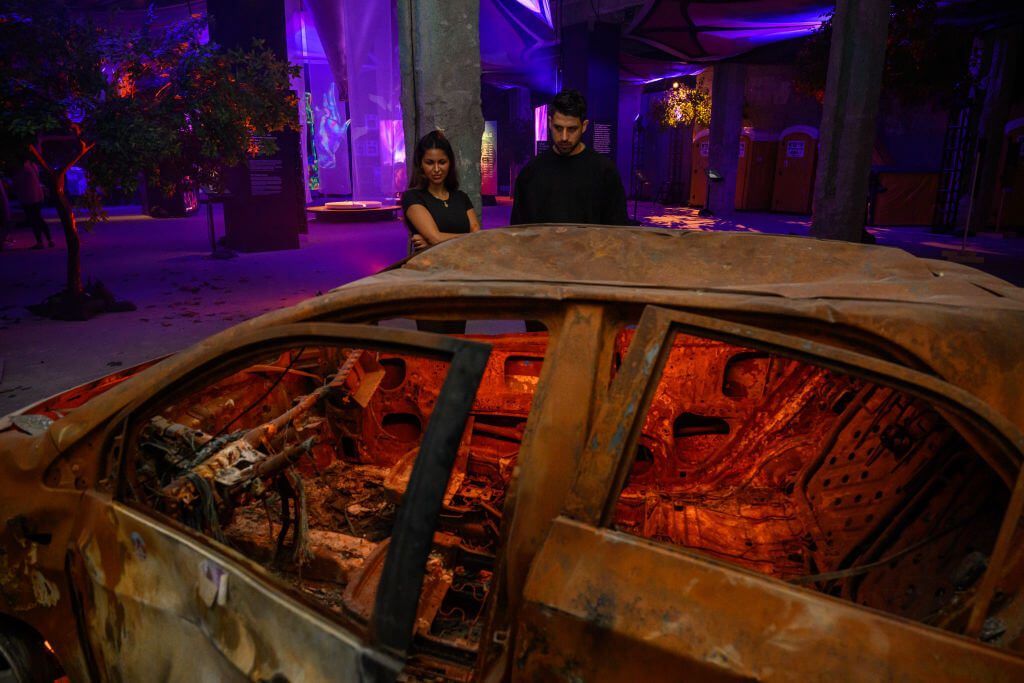 Nova survivor Natalie Sanandaji, and Reef Peretz, Chairman of the Nova Foundation, look at destroyed cars taken from the Nova festival at "The Nova Music Festival Exhibition" in April 2024 in New York City.