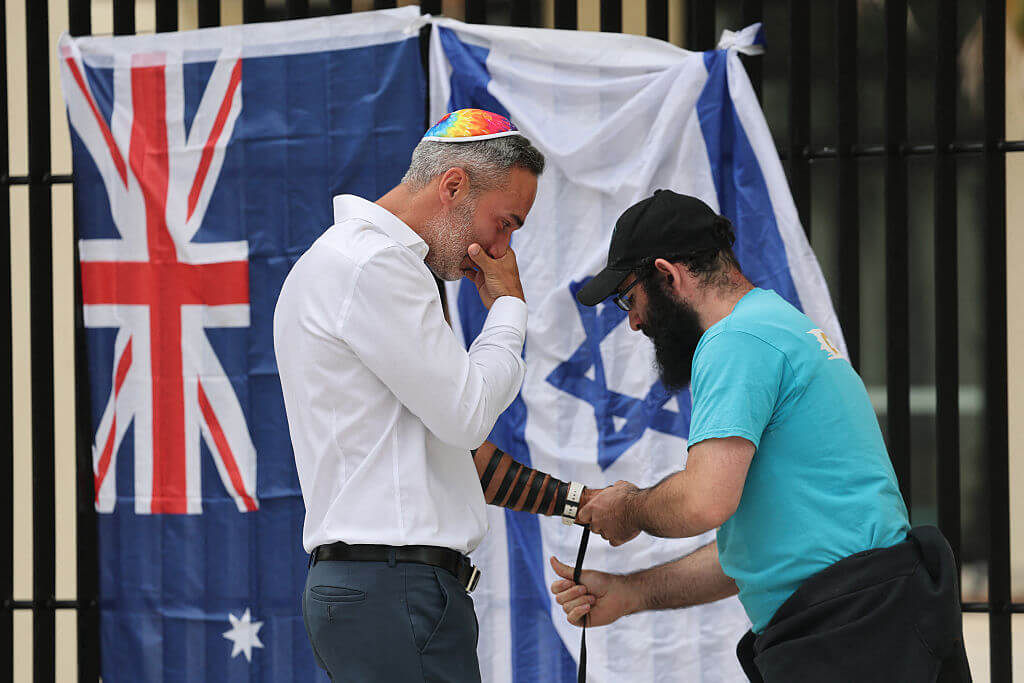 Co-CEO of the executive council of Australia Jewry Alex Ryvchin (L) prays with a rabbi as they stand outside the Bondi Pavilion, where an Australia and Israeli flag are displayed in memory of the victims of a shooting at Bondi Beach, in Sydney on December 15, 2025.
