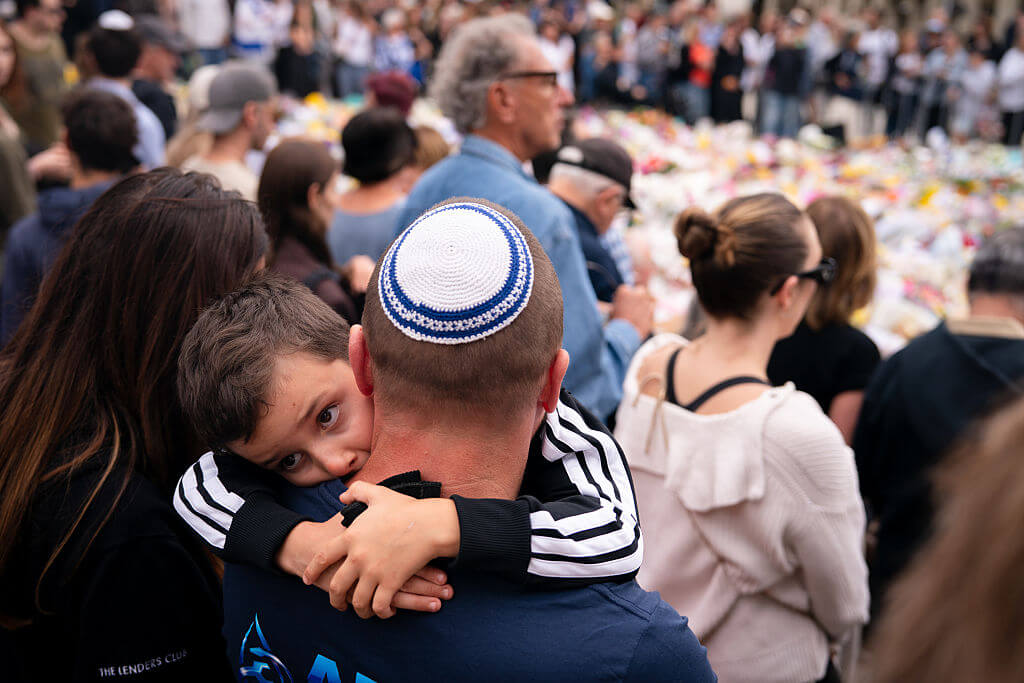 Jagger Blewitt, 5, hangs on to his father, Trent Blewitt, during a vigil at Sydney's Bondi Beach on December 16.