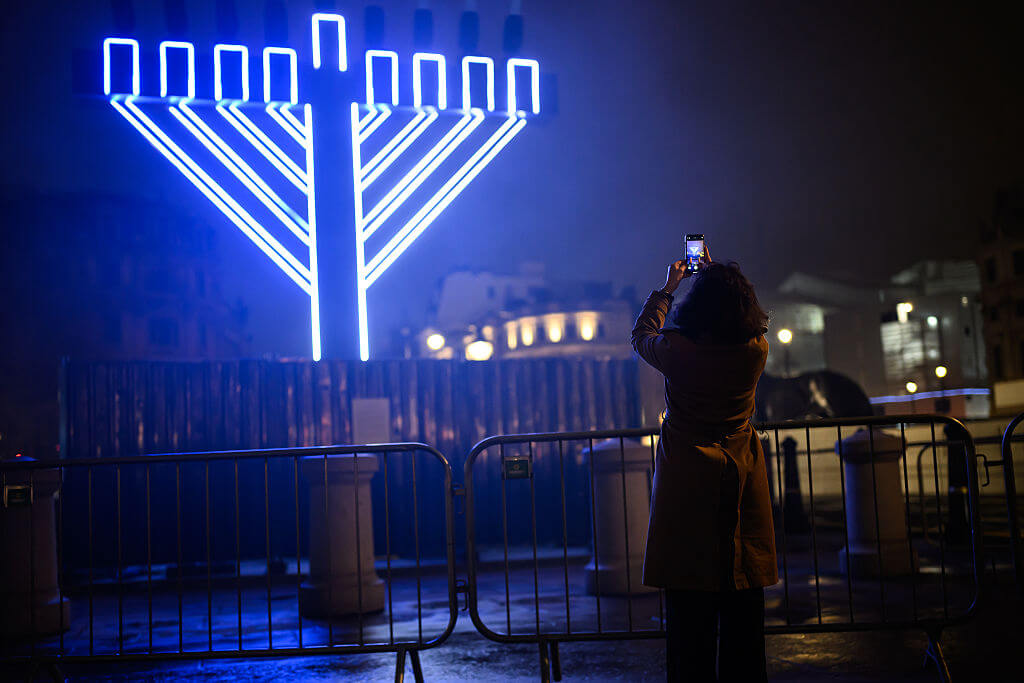 People stop to look at an illuminated Menorah during Hanukkah concert at Trafalgar Square in London on December 16.