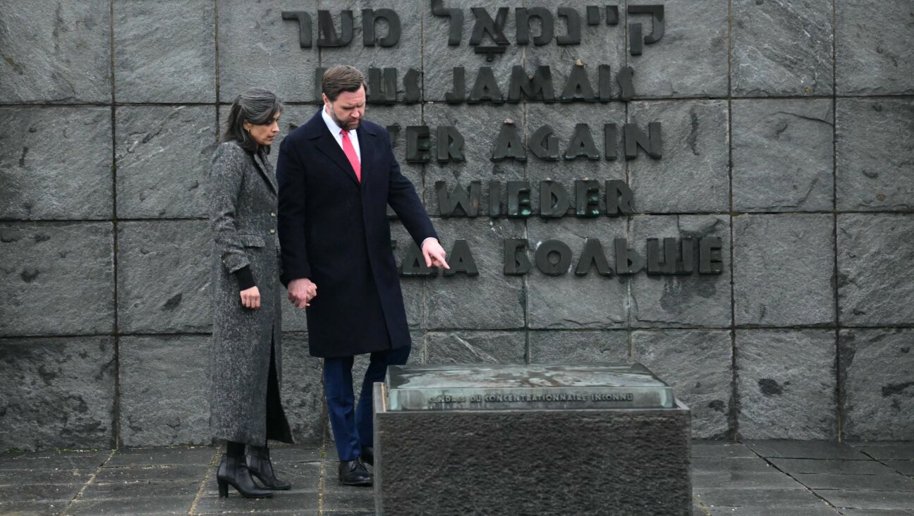 US Vice President JD Vance (R) and his wife Usha Vance (L) visit the gravestone with the ashes of an unknown prisoner and the wall with the inscription "Never again" in five languages, during a tour of the Dachau Concentration Camp memorial site in Dachau, southern Germany, on February 13, 2025.