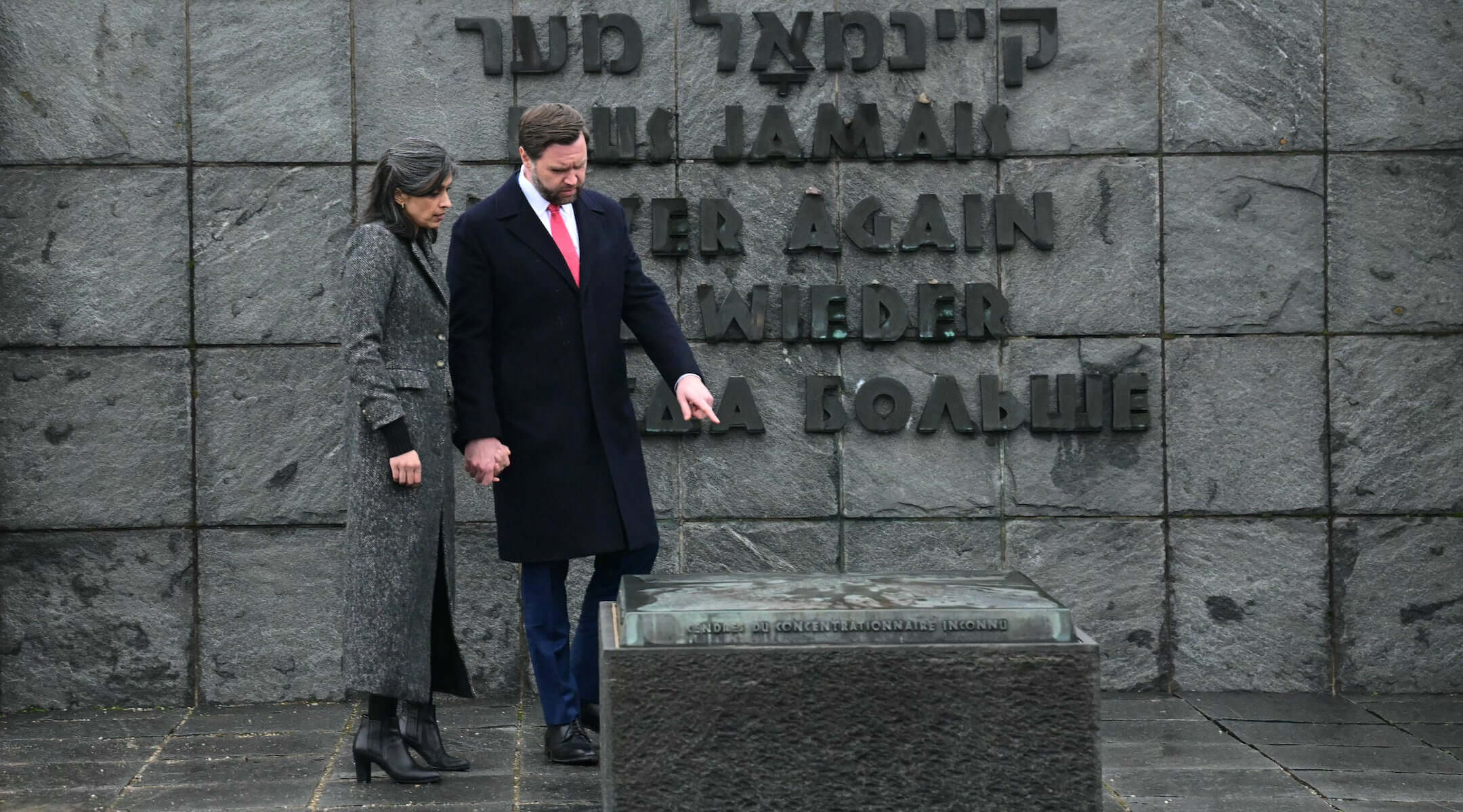 US Vice President JD Vance (R) and his wife Usha Vance (L) visit the gravestone with the ashes of an unknown prisoner and the wall with the inscription "Never again" in five languages, during a tour of the Dachau Concentration Camp memorial site in Dachau, southern Germany, on February 13, 2025.