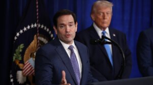 Secretary of State Marco Rubio speaks during a press conference as U.S. President Donald Trump listens at Mar-a-Lago club on January 03, 2026, in Palm Beach, Florida. During the event, President Trump confirmed that the U.S. military carried out a large-scale strike in Caracas overnight, resulting in the capture of Venezuelan leader Nicolas Maduro and his wife, Cilia Flores. 