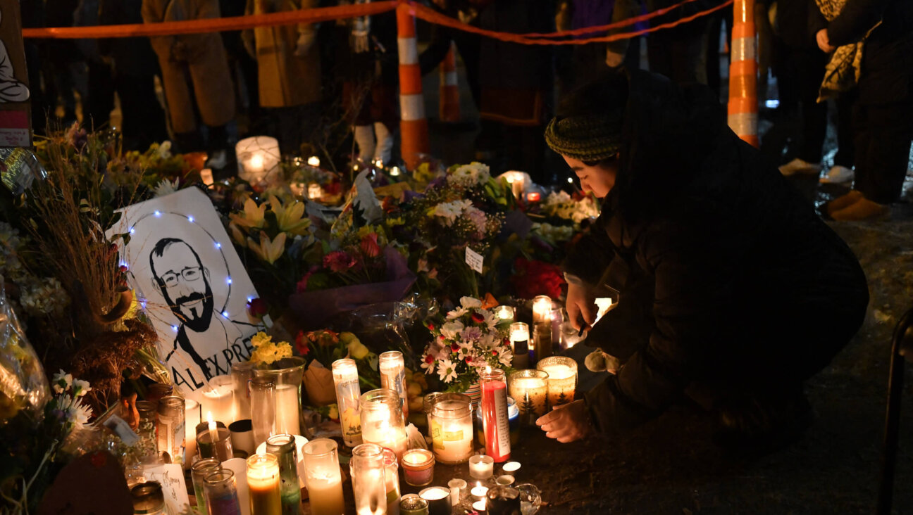 A woman lights a candle on Jan. 26 while mourning at a makeshift memorial in the area where Alex Pretti was shot dead by federal immigration agents in Minneapolis, Minnesota.