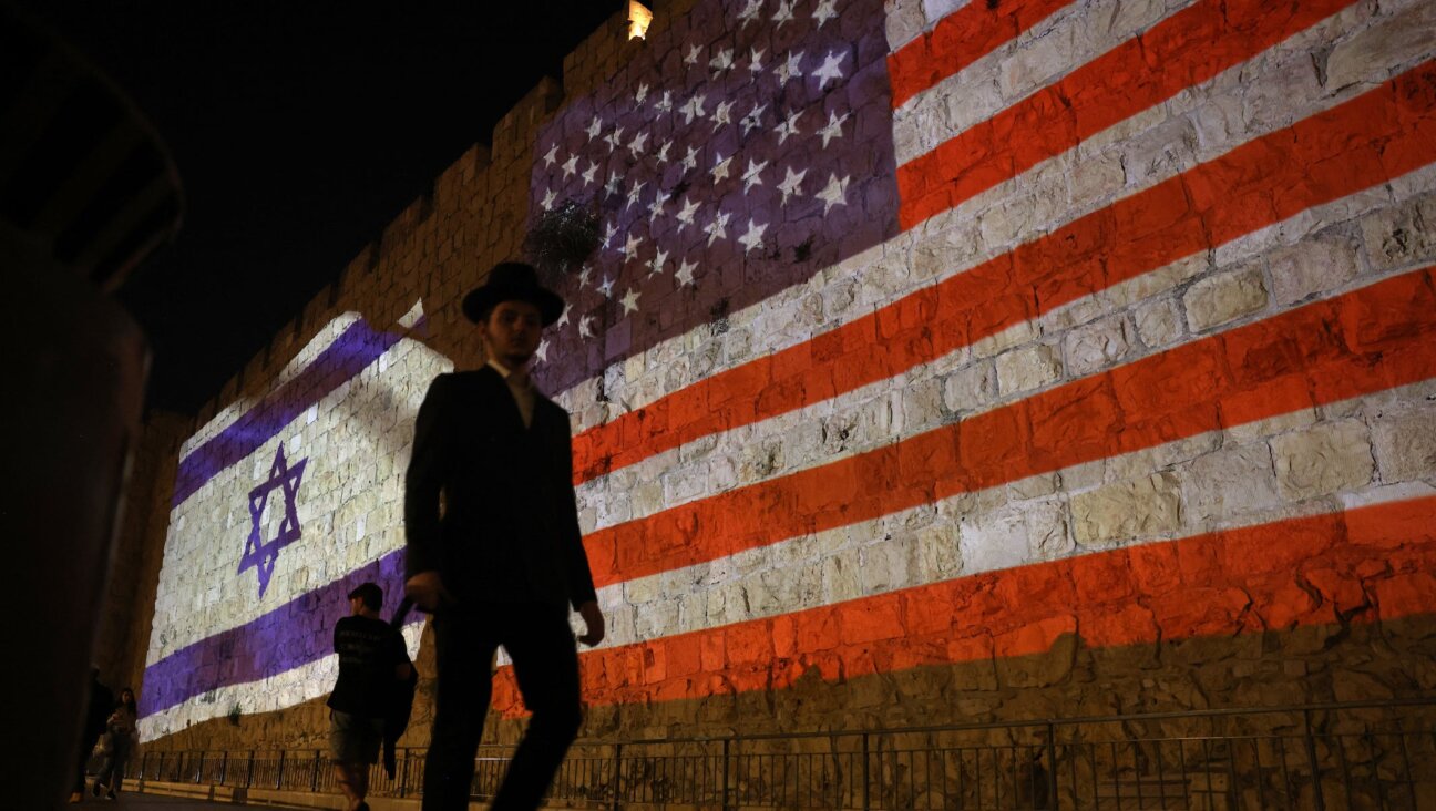 People walk past a projection depicting Israeli and US flags on the walls of Jerusalem’s Old City on Oct. 22, 2025.